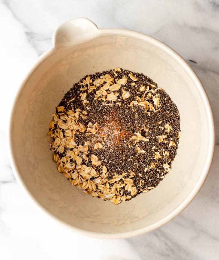 Dry rolled oats, cinnamon, salt, and chia seeds in a bowl