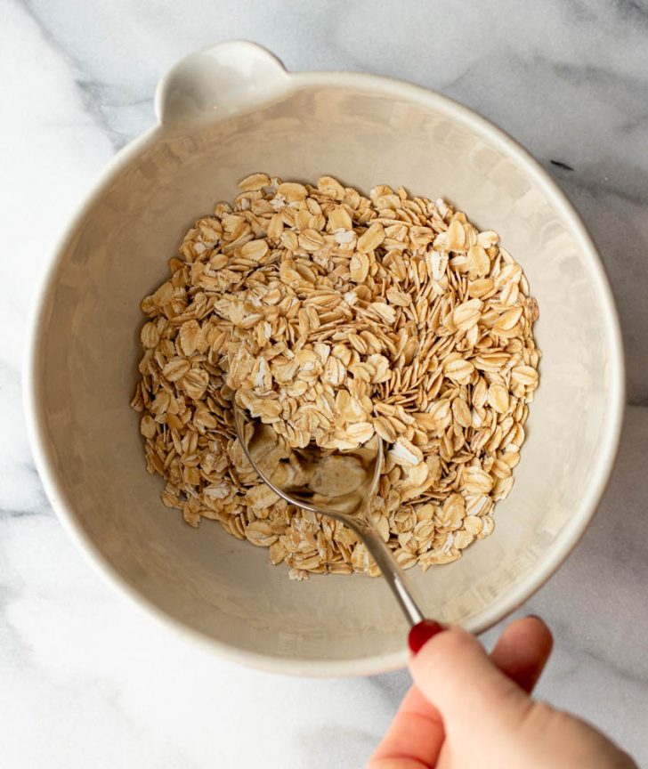 hand mixing up dry oatmeal in a bowl with a spoon