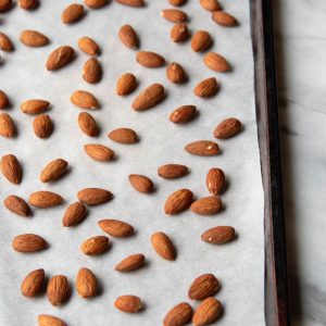 whole almonds on a baking sheet with white parchment paper