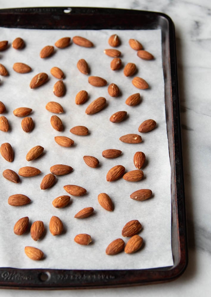 whole almonds on a baking sheet with white parchment paper