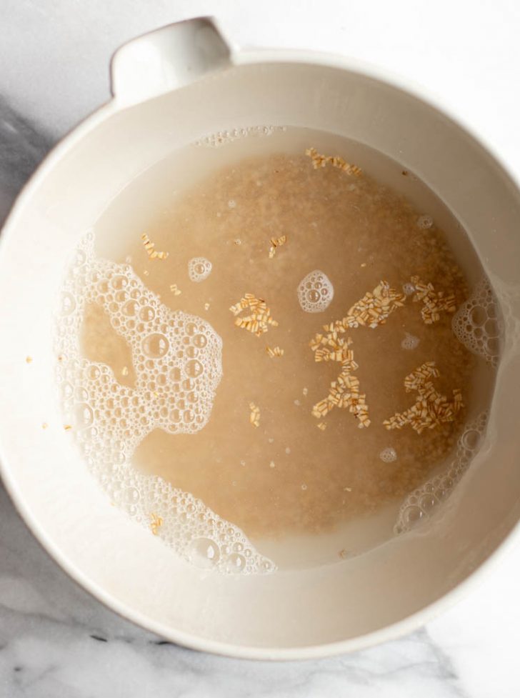 steel cut oats and water in a large white bowl before being cooked in the microwave