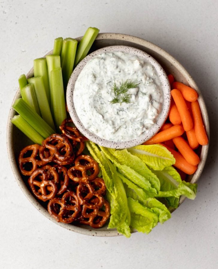 a bowl of raw veggies and pretzels with a smaller bowl of greek yogurt dill dip