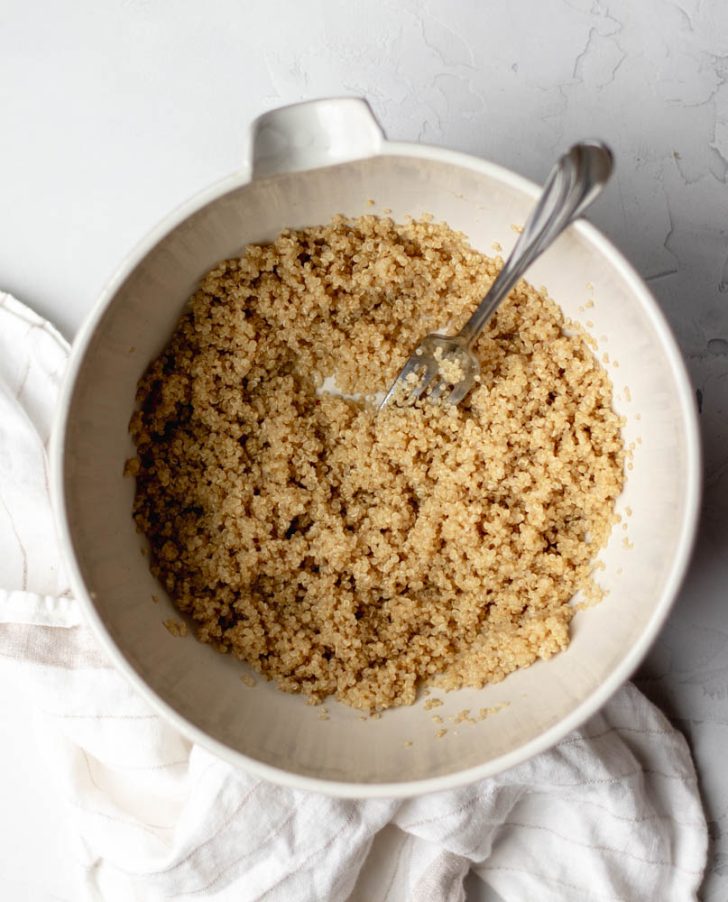 cooked quinoa in a white bowl with fork 
