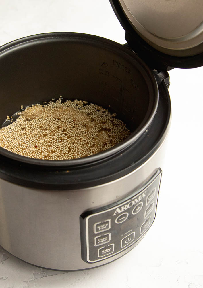 Quinoa and water in a rice cooker that is opened