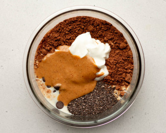chocolate peanut butter overnight oats ingredients in a glass circular container before being mixed