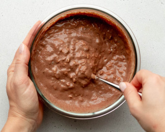 hands mixing up a container of chocolate peanut butter overnight oats