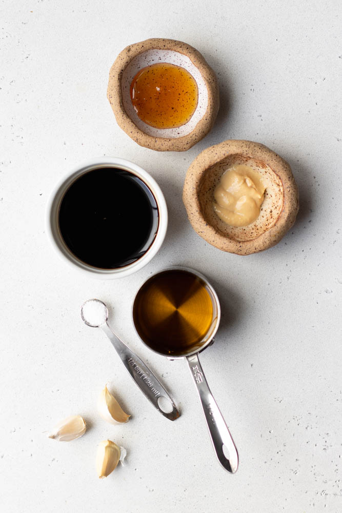 Honey balsamic vinaigrette ingredients measured out on a light grey backdrop