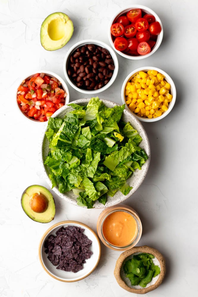 vegetarian taco salad ingredients measured out in bowls on a white backdrop