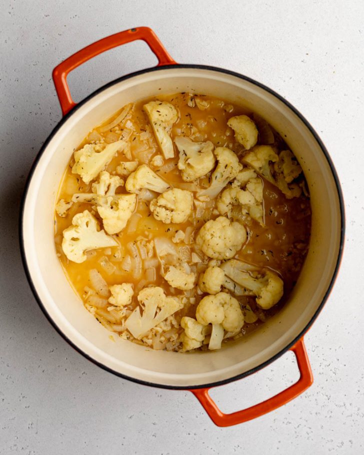 Cauliflower, garlic, and onions in a pot with veggie broth