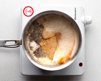 Small saucepan with oats, chia seeds, and flax on a white burner