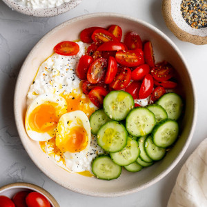 savory cottage cheese breakfast bowl on light grey backdrop surrounded by ingredients