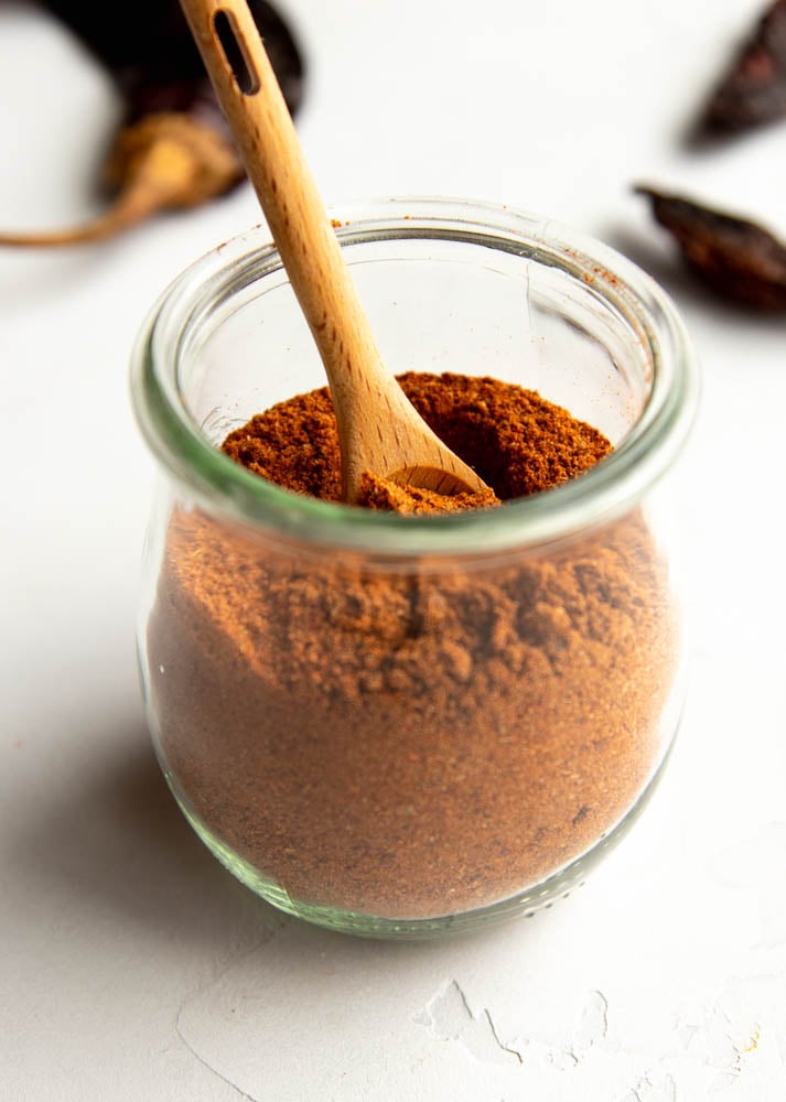 small jar of homemade chili powder with a small wooden spoon