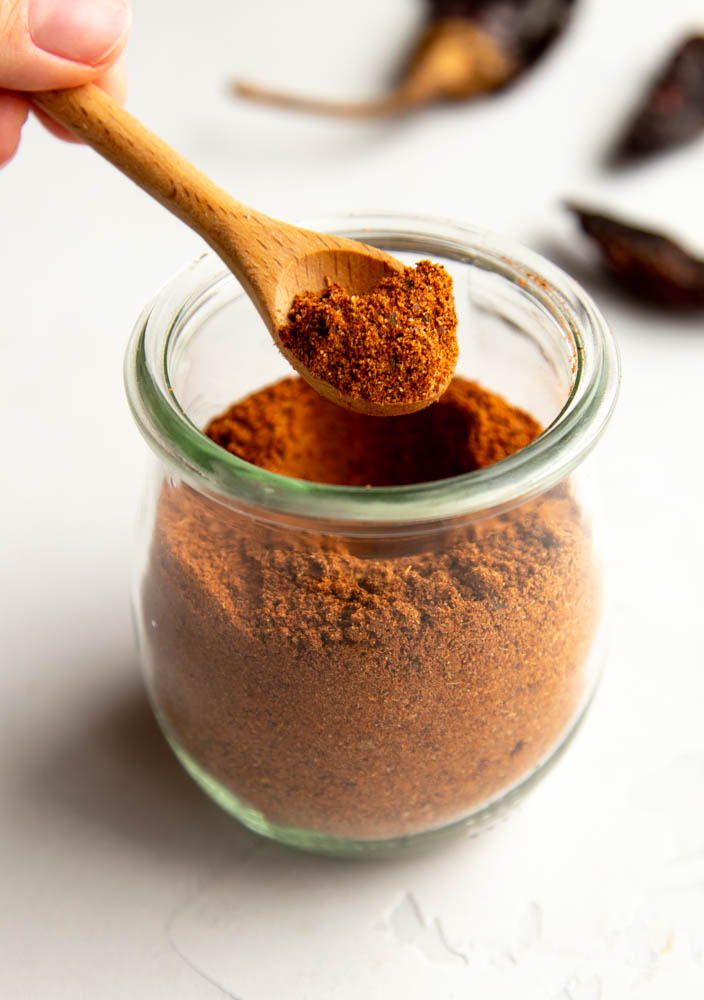 small jar of homemade chili powder with a small wooden spoon
