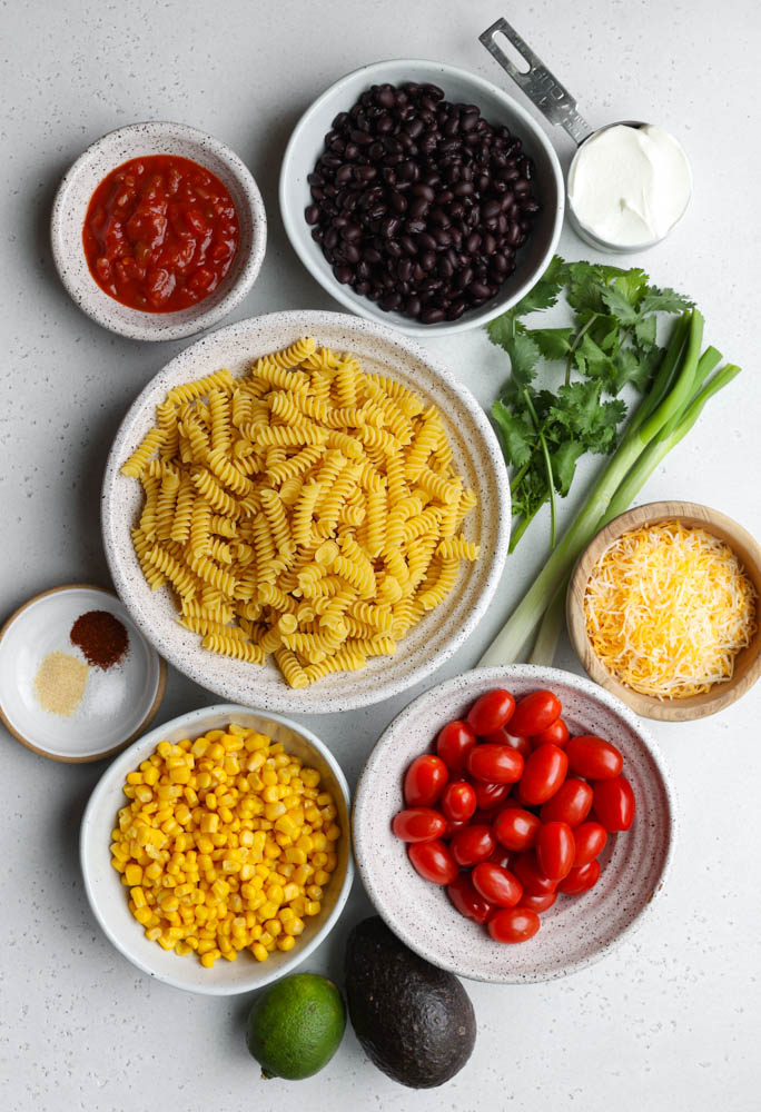 taco pasta salad ingredients measured out on a light grey backdrop