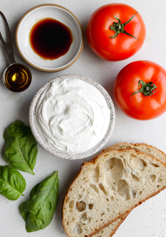 Tomato basil cottage cheese toast ingredients on a light grey backdrop