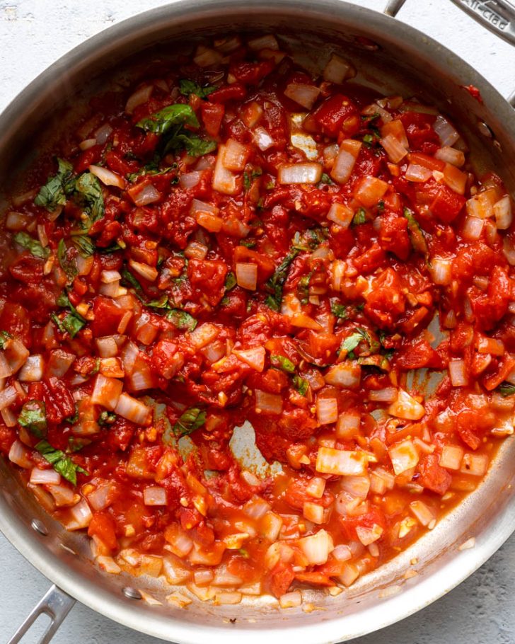 tomato basil sauce being cooked in a stainless steel saute pan