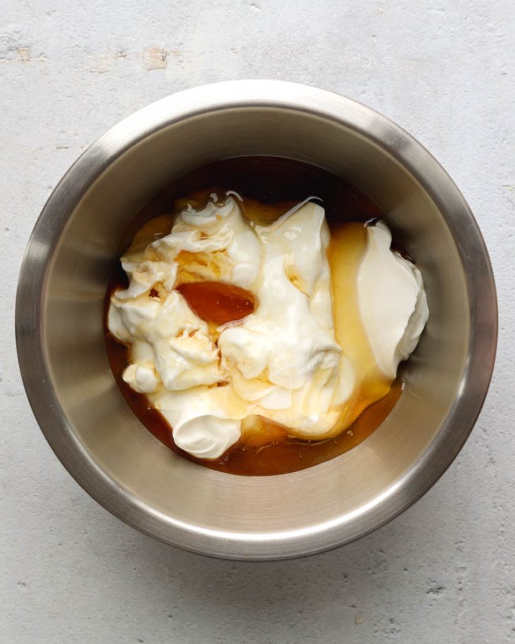 Greek yogurt, honey, and vanilla extract in a metal mixing bowl