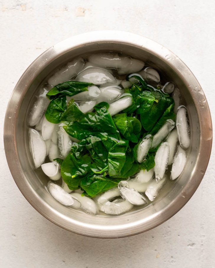 blanched spinach in a bowl of ice water