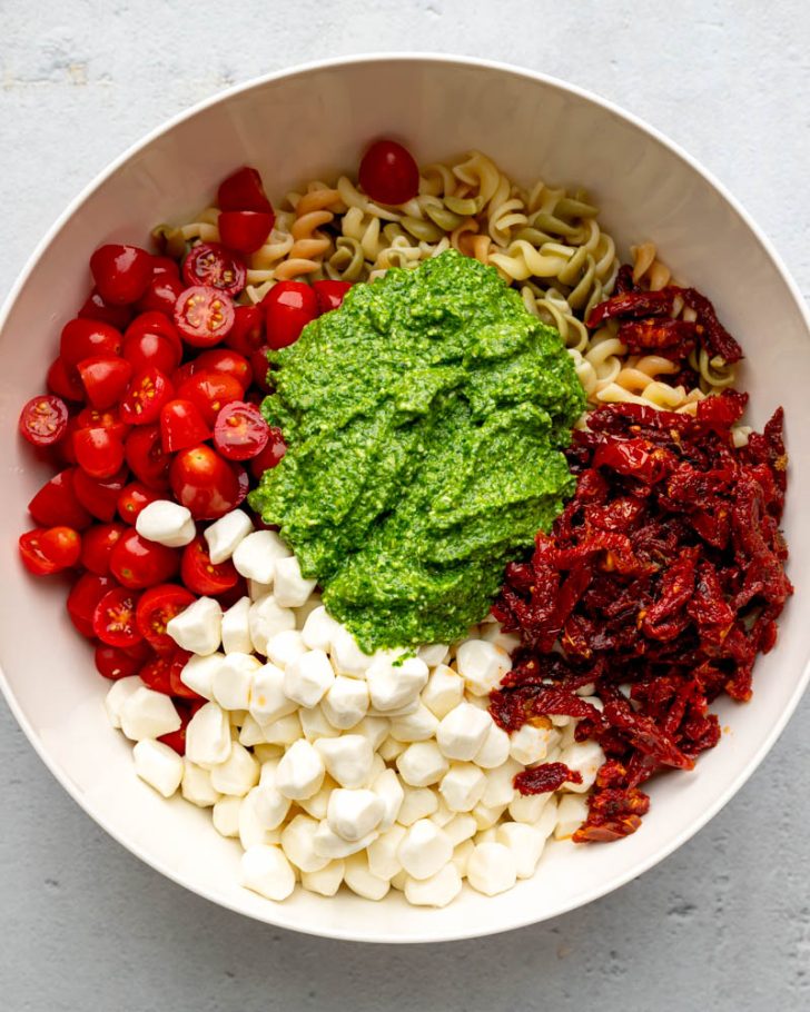 tri color pasta salad ingredients in a mixing bowl before being mixed