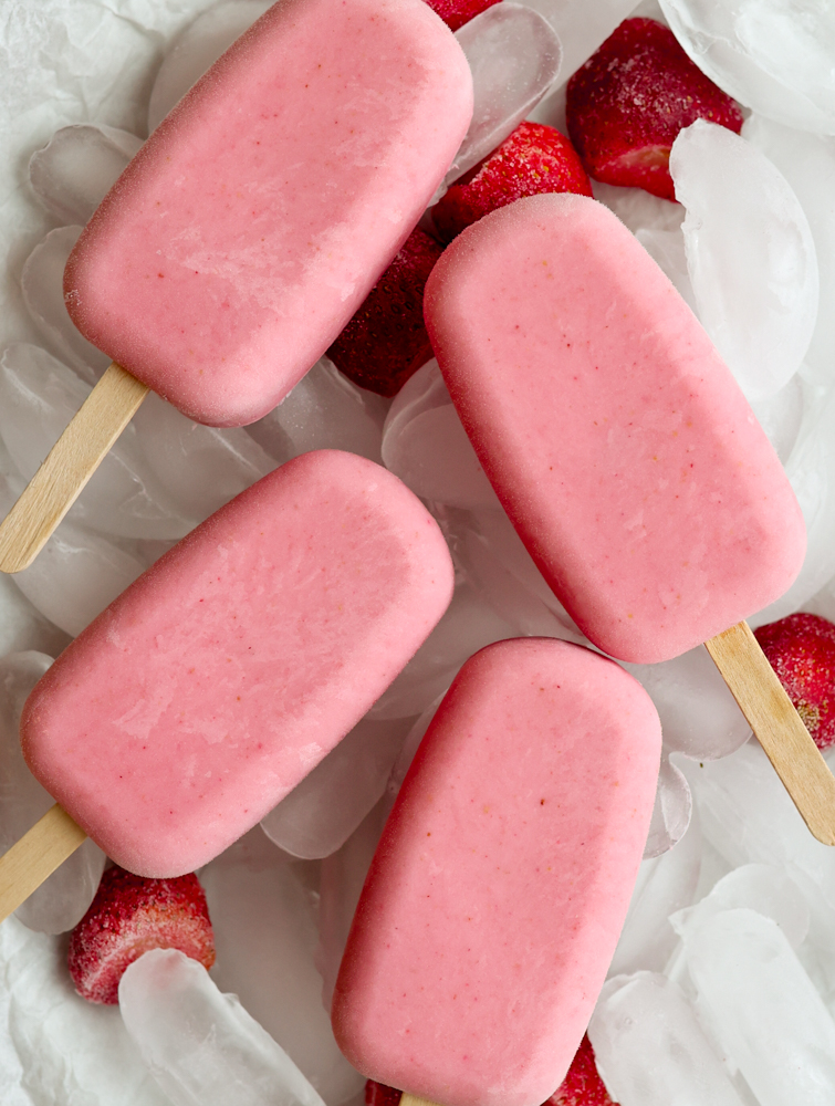 4 strawberry popsicles on a plate with ice