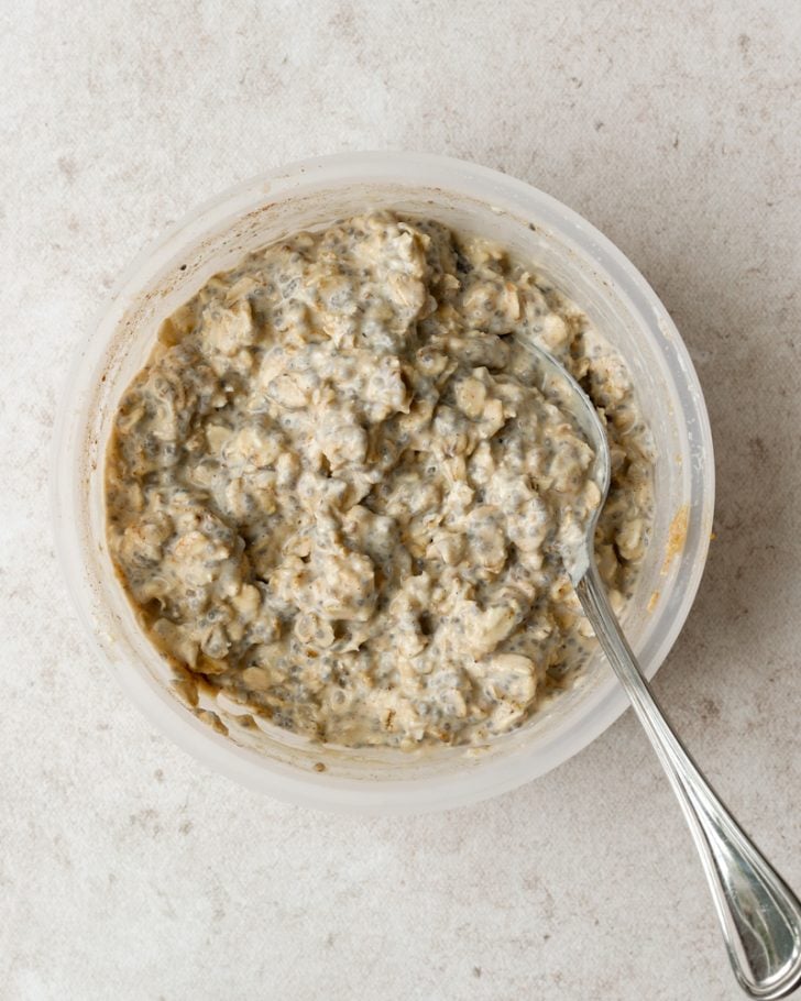overnight oats in a round tupperware with a silver spoon