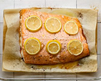 Roasted salmon fillet with lemon slices on parchment paper