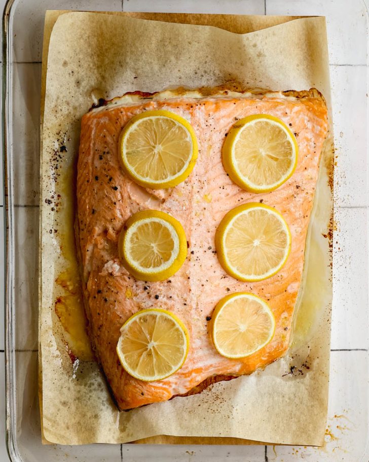Roasted salmon fillet with lemon slices on parchment paper