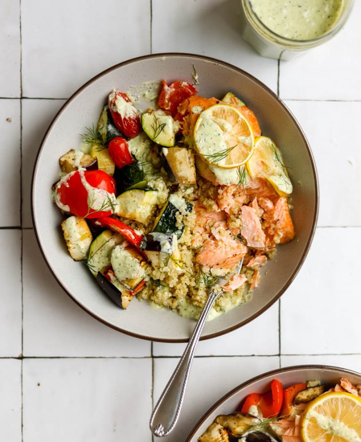 Mediterranean salmon quinoa bowl on a white tiled backdrop