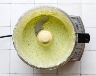 Feta dill dressing in a food processor on a white tile backdrop