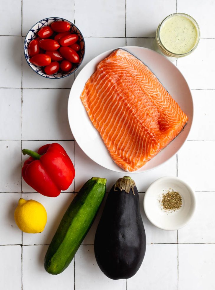 salmon quinoa bowls ingredients measured out on white tiled backdrop