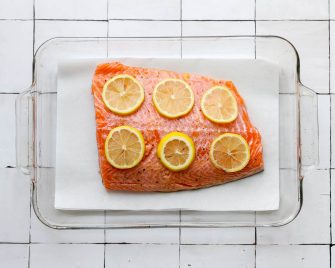 Salmon filet in a glass baking dish with lemon slices