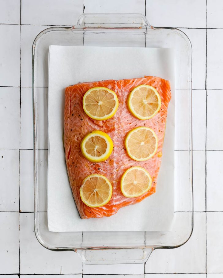 Salmon filet in a glass baking dish with lemon slices