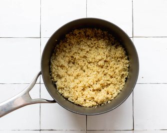 Cooked quinoa in a pot on a white tile backdrop