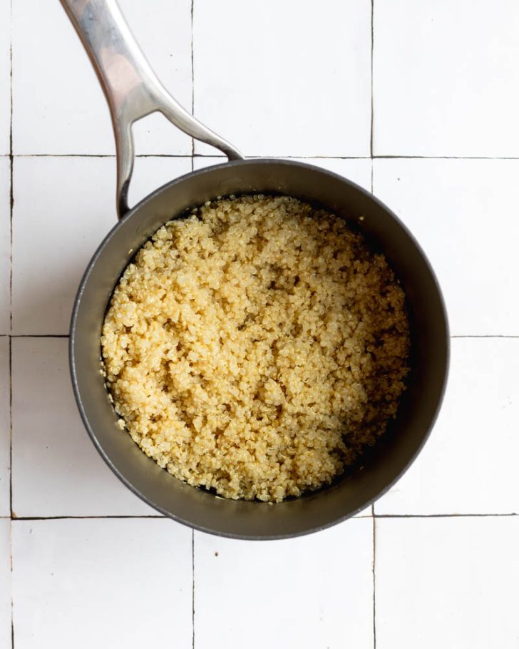 Cooked quinoa in a pot on a white tile backdrop