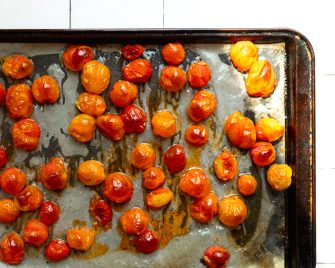 Roasted cherry tomatoes on a parchment paper lined baking sheet