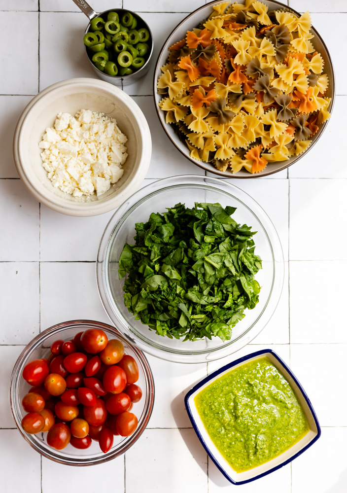 bowtie pasta salad ingredients measured out on a light tiled backdrop
