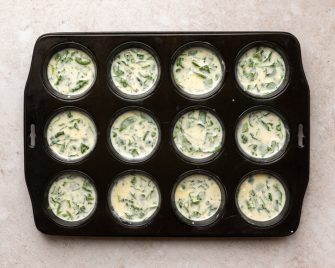 egg bites in a muffin tin before being baked