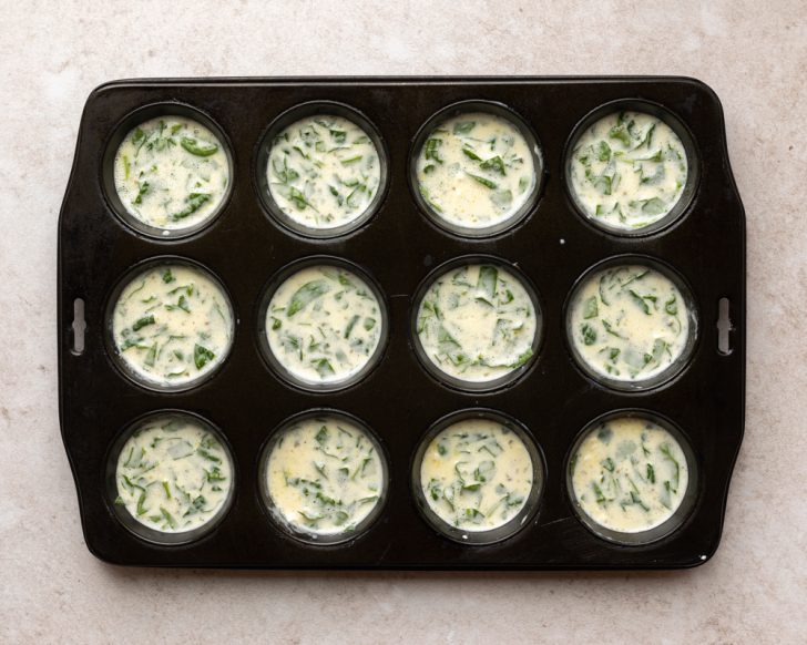 egg bites in a muffin tin before being baked
