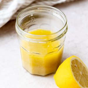 Jar of lemon dijon dressing next to lemon halves