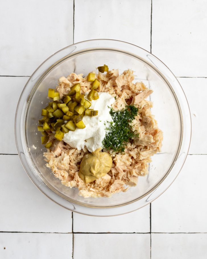 tuna salad ingredients in a glass mixing bowl before getting mixed together