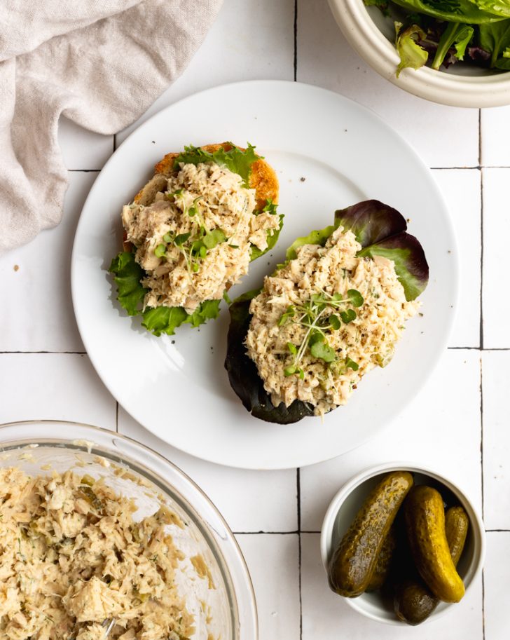 tuna salad with lettuce on sliced bread, on a white plate