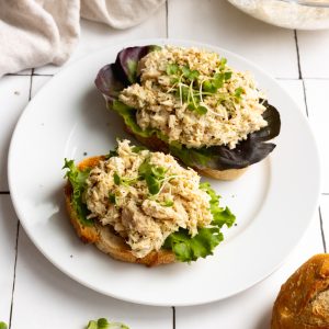 tuna salad with lettuce on sliced bread, on a white plate