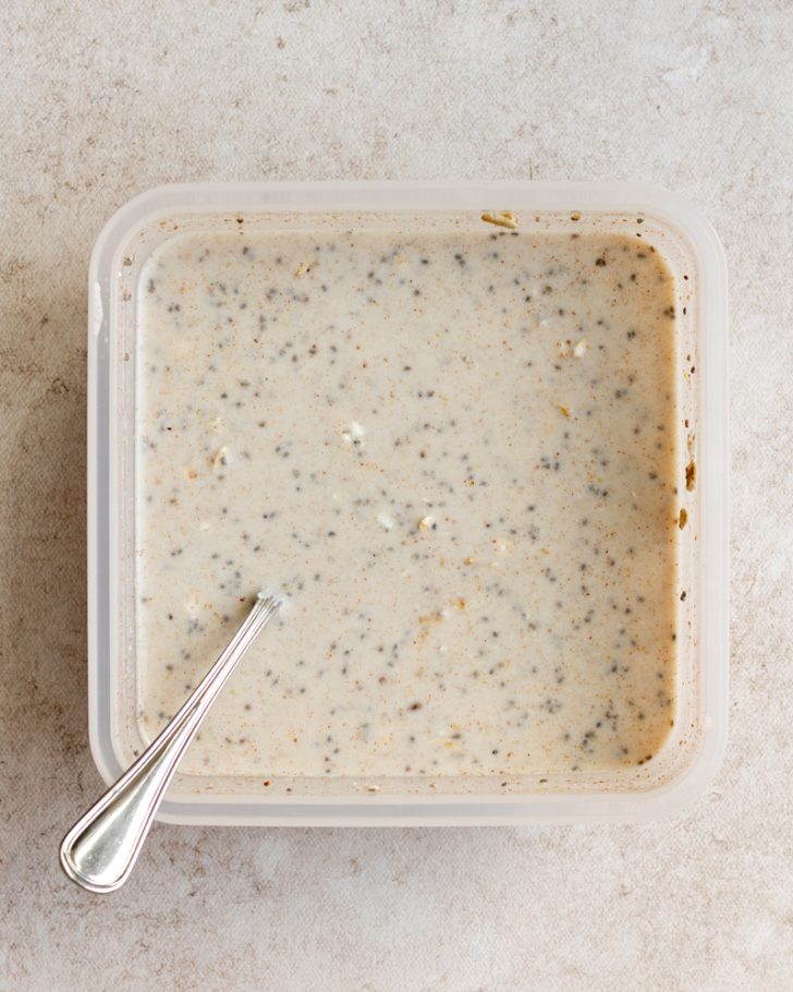 overnight oats mixed together in square tupperware with a silver spoon