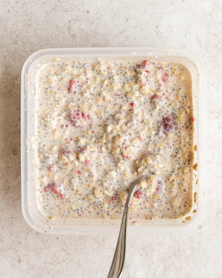 Overnight oats in a square tupperware container with a silver spoon