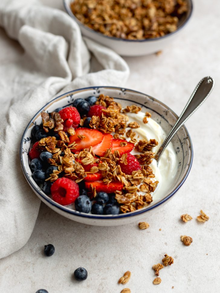 yogurt and granola bowl with fresh berries and a silver spoon