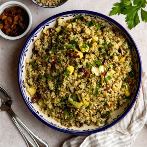 lentil quinoa salad in a blue rimmed serving bowl with silver serving spoons