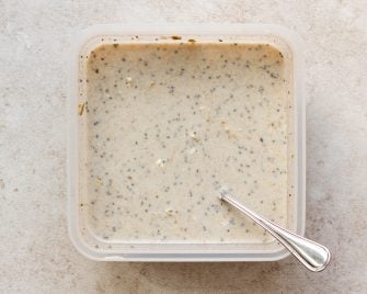 overnight oats mixed together in square tupperware with a silver spoon