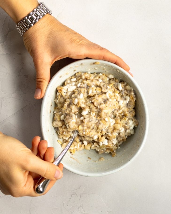 hands mixing up a bowl of oats with cottage cheese