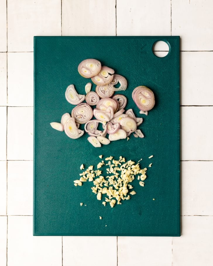 sliced shallots and minced garlic on a teal cutting board