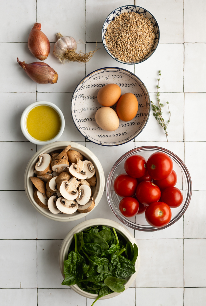farro grain bowl ingredients measured out on a white tile backdrop